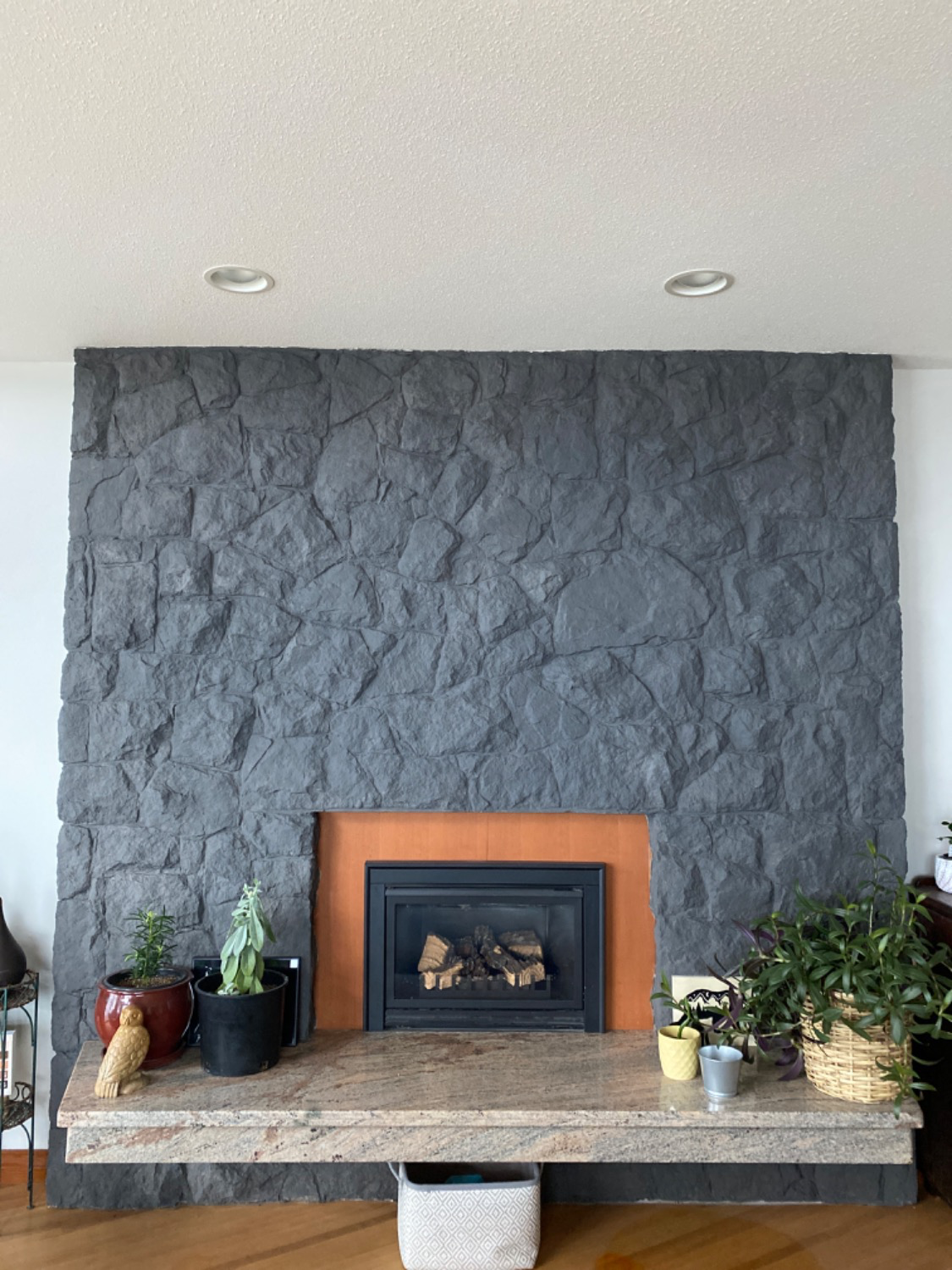 Charcoal grey painted stone fireplace wall with orange tiles